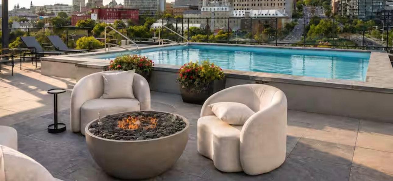 Piscine sur le toit avec fauteuils blancs et foyer extérieur, vue sur Québec